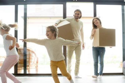 kids playing in new home parents holding boxes moving day