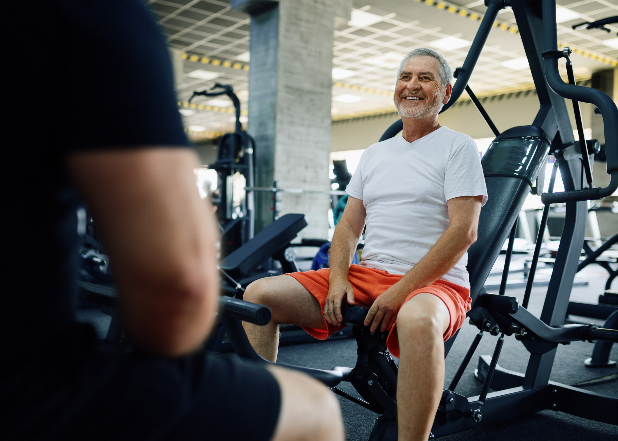 older man working out at gym with trainer