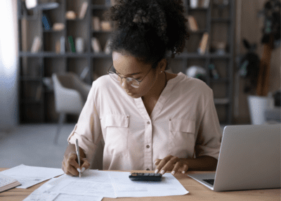 women budgeting using calculator at desk in office